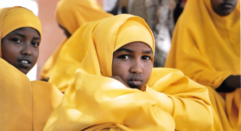 Girl in yellow hijab sits among peers